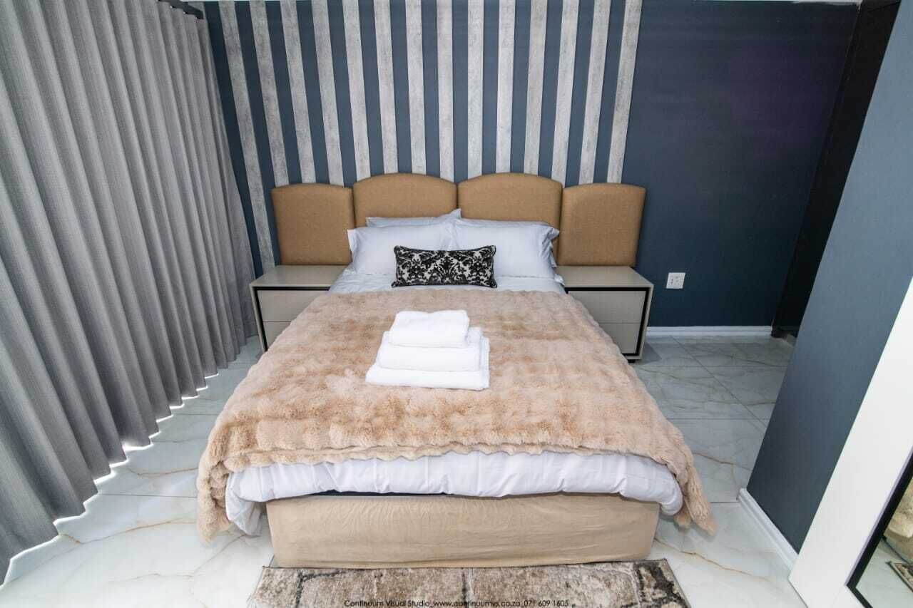 Un dormitorio con cama, dos mesitas de noche, cabecera y cortina.