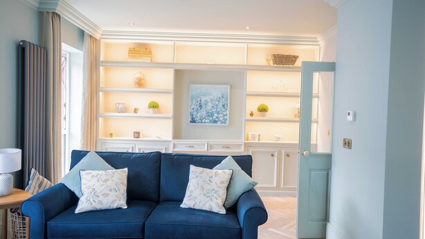 A living room with a blue sofa, a lamp, and a bookshelf.