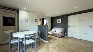 Una habitación moderna y luminosa con una mesa de comedor y sillas, un sofá y un armario.