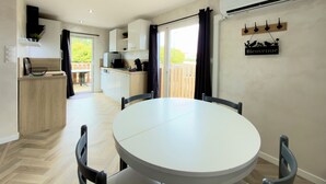 Una cocina moderna con comedor, puerta corrediza de vidrio al exterior y un letrero de bienvenida.