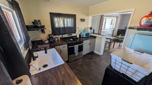 A compact kitchen with a sink, stove, microwave, and a dining area with a table and chairs. - Farmhouse Studio just minutes from uptown. (Butte)