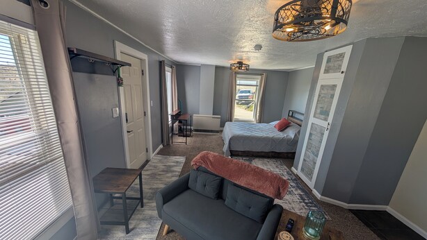 A compact living space with a sofa, a bed, a desk, and a ceiling light fixture. - Farmhouse Studio just minutes from uptown. (Butte)