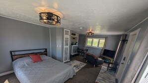 A bedroom with a bed, a desk, a TV, and a window. - Farmhouse Studio just minutes from uptown. (Butte)
