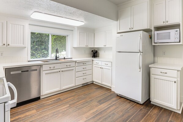 Enjoy cooking in this well-lit kitchen with a microwave, stainless steel dishwasher, and white cabinetry.