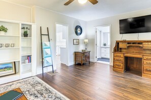 Relax in this stylish living room with a flat-screen TV, desk, and shelving unit.