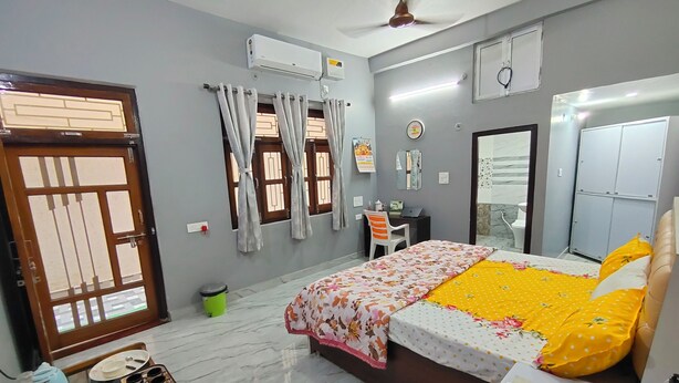 Un dormitorio con cama, escritorio, silla, armario y baño.