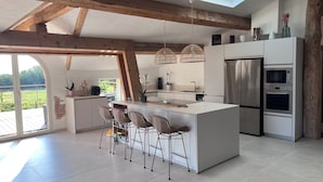 A modern kitchen with a large island, built-in appliances, and a skylight. - Domaine Villadomar: Farmhouse nestled in the heart of Thuir in the calm of its wooded grounds (thuir)