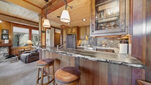 A rustic kitchen with wooden cabinets, a granite countertop, and two bar stools.