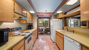A compact kitchen with wooden cabinets, a stove, a refrigerator, and a dishwasher. - Nestled in the heart of Graeagle Meadows, Private Fenced Yard, Sleeps 6 (Graeagle)