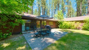 A patio with outdoor furniture, a grill, and a view of tall trees. - Nestled in the heart of Graeagle Meadows, Private Fenced Yard, Sleeps 6 (Graeagle)