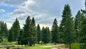 Golfkenttä, jossa on lampi, puita ja klubitalo.