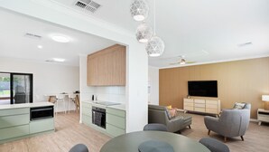 A modern kitchen with a built-in oven and a dining area with a round table. - Granite Grove - Port Elliot (Port Elliot)