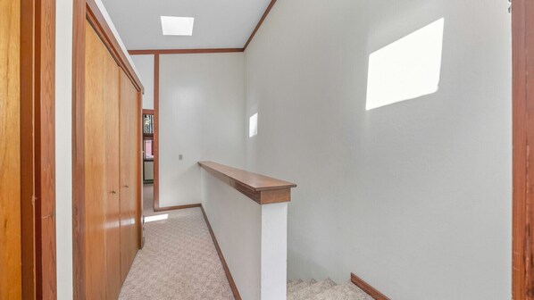 Un couloir étroit avec un plancher en bois, un mur blanc et un banc en bois.
