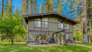 A two-story building with a patio area, outdoor seating, and a covered barbecue grill. - Enjoy the beauty of Graeagle Meadows Golf Course and from this charming mountain retreat! (Graeagle)