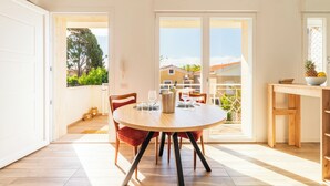 Un coin repas avec une table ronde, des chaises et une vue sur un quartier résidentiel, grâce à de grandes portes coulissantes.