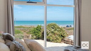 A room with a large window offering a view of the beach and ocean.