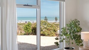 A room with a large window offering a view of the beach and ocean.
