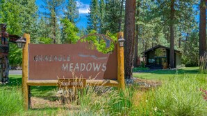 A sign for Graeagle Meadows with a wooden bench in front.
