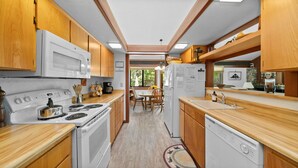 A compact kitchen with wooden cabinets, a microwave, stove, refrigerator, and dishwasher.