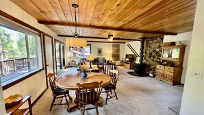 Un espace repas avec une table et des chaises en bois, un mur en pierre et une vue sur l’extérieur.