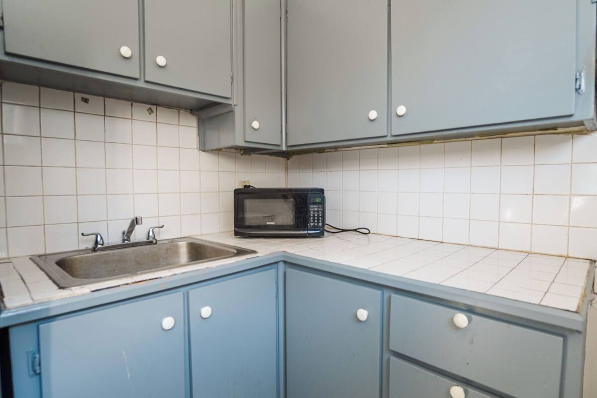 Una cocina con armarios azules, un microondas y un lavamanos.