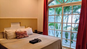Una habitación de hotel con una cama grande, una mesita de noche y una ventana con cortinas.