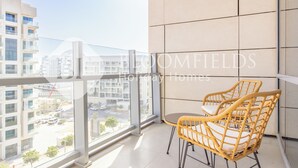 A balcony with wicker chairs and a view of the cityscape. - Bloomfields Grandeur 1BR In Lamar Raha (Abu Dhabi)