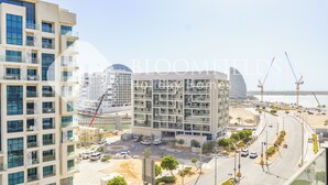A modern building with multiple floors, large windows, and a central courtyard. - Bloomfields Grandeur 1BR In Lamar Raha (Abu Dhabi)