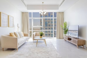 A modern living room with a sofa, a coffee table, a TV, and a large window with a city view.