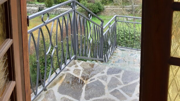 A stone staircase leading to a balcony with a metal railing, overlooking a hillside with buildings and trees. - Detached house in a property at the entrance to the Restonica valley (Corte)