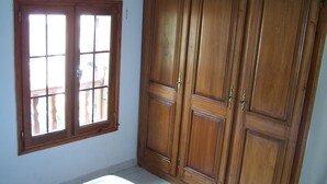 A bedroom with a large wooden wardrobe, a window with a balcony, and a bed. - Detached house in a property at the entrance to the Restonica valley (Corte)