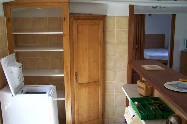 Cocina compacta con lavadora, un armario de madera y un organizador de utensilios verde.