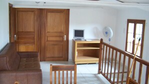 A room with a brown sofa, a wooden chair, a TV on a wooden stand, and a window with a view of the outside. - Detached house in a property at the entrance to the Restonica valley (Corte)