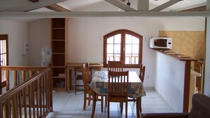 A dining area with a table, chairs, and a fan. There is a kitchen area with a microwave and a window. - Detached house in a property at the entrance to the Restonica valley (Corte)