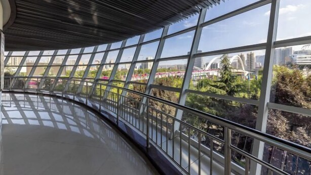 Ein großzügiges, modernes Interieur mit großen Fenstern und Blick auf Stadt und Grünflächen.