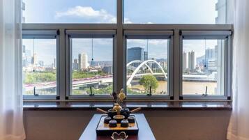 Ein Zimmer mit großem Fenster und Blick auf eine Stadtlandschaft, einschließlich einer Brücke und Gebäuden.