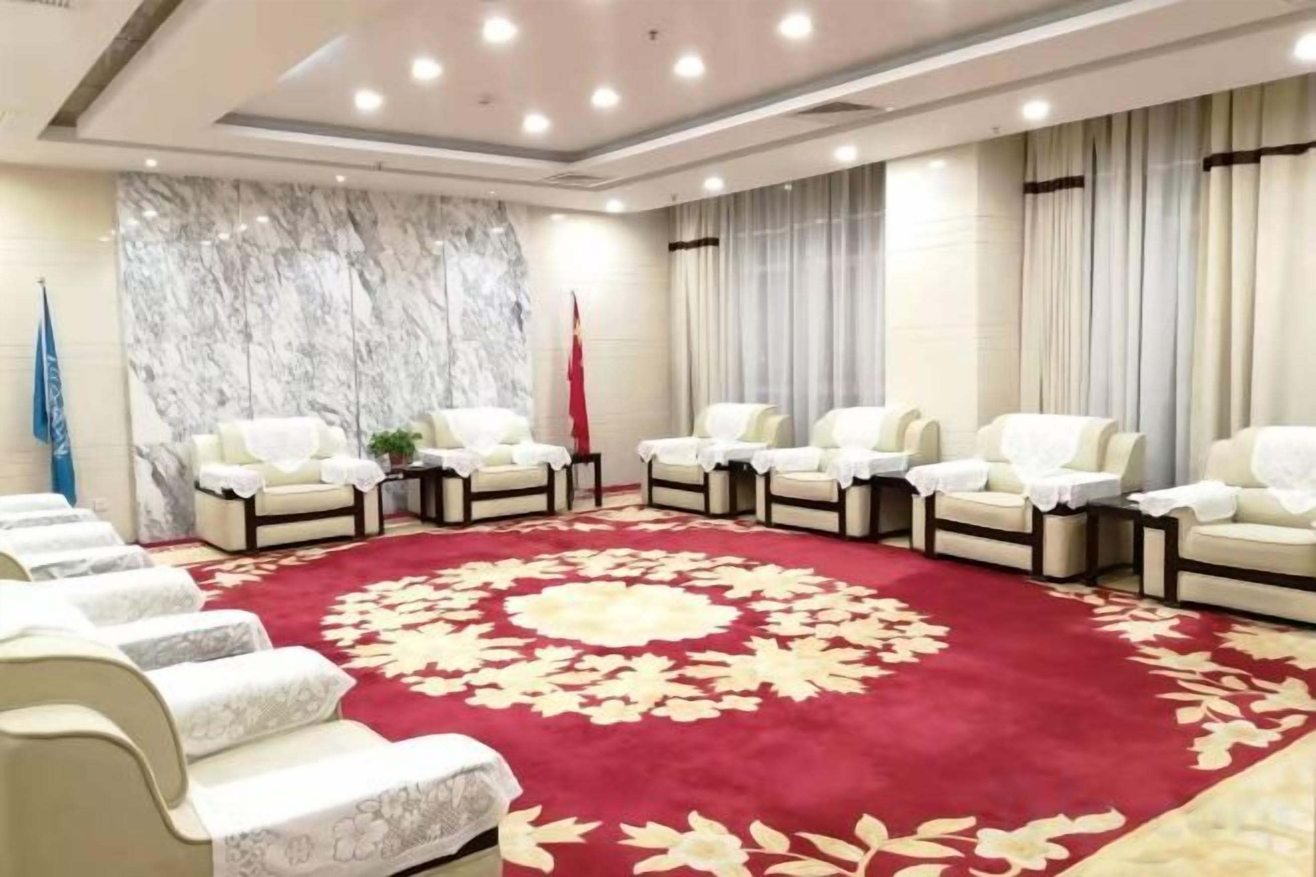 A conference room with a red carpet, white chairs, and a flag.