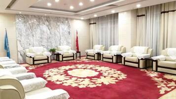 A conference room with a red carpet, white chairs, and a flag.