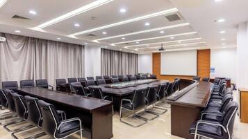 A conference room with a long table, multiple chairs, and a projector screen.
