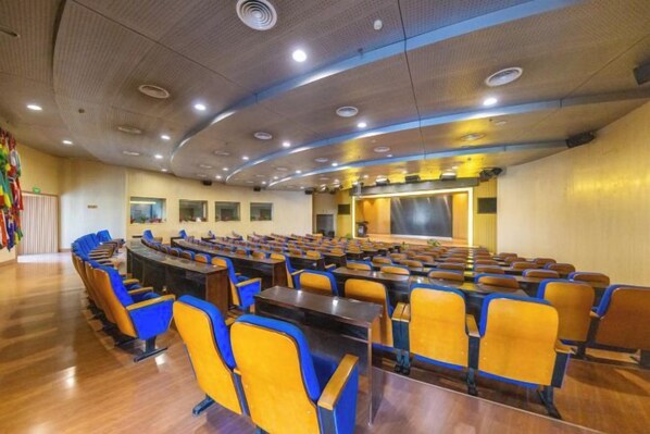 A conference room with a long table and chairs, a stage, and a large screen. - Golden Camel International Hotel (Lanzhou International Convention and Exhibition Center) (Lanzhou)
