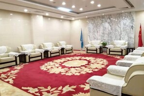 A conference room with a red carpet, rows of white chairs, and flags. - Golden Camel International Hotel (Lanzhou International Convention and Exhibition Center) (Lanzhou)