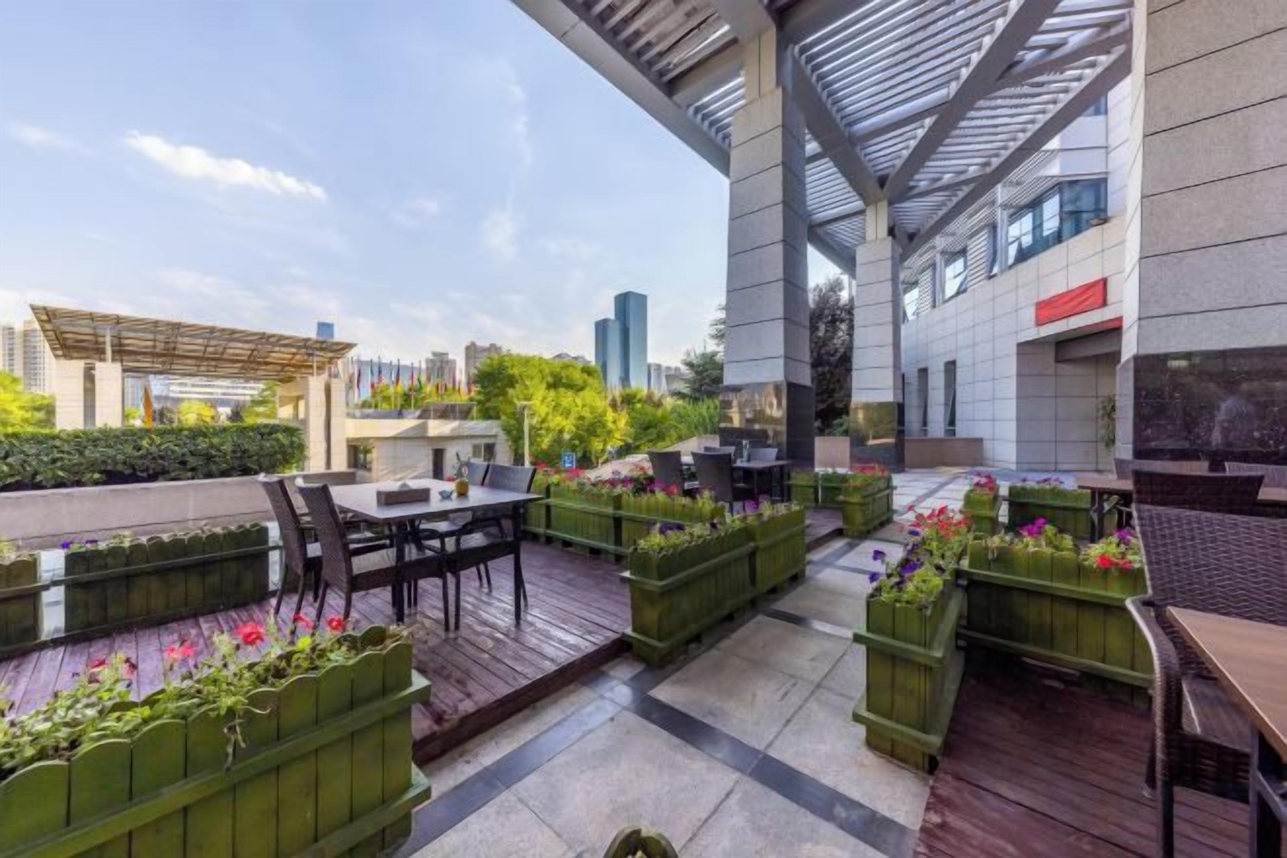 An outdoor patio area with seating and planters, surrounded by a modern building structure.