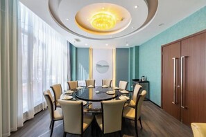 A conference room with a round table, chairs, a chandelier, and a view through large windows. - Golden Camel International Hotel (Lanzhou International Convention and Exhibition Center) (Lanzhou)
