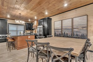 Enjoy meals in the spacious kitchen and dining area with a central island, large wooden table, and mountain views.