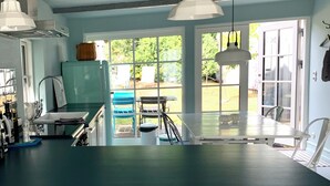 A kitchen with a teal countertop, white cabinets, and a window overlooking a garden.