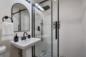 A modern bathroom with a glass-enclosed shower, a white sink with black fixtures, and a mirror above the sink. - Kings Beach Cabin | 5-Min Walk to Sand & Shops (Kings Beach)