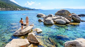 A clear lake with rocky formations and people standing on rocks. - Walk to Kings Beach | Summer Cabin Retreat! (Kings Beach)