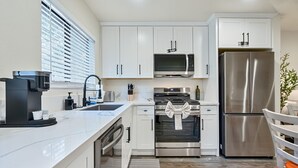 A modern kitchen with white cabinets, a stainless steel refrigerator, a microwave, and a gas stove. - Walk to Kings Beach | Summer Cabin Retreat! (Kings Beach)