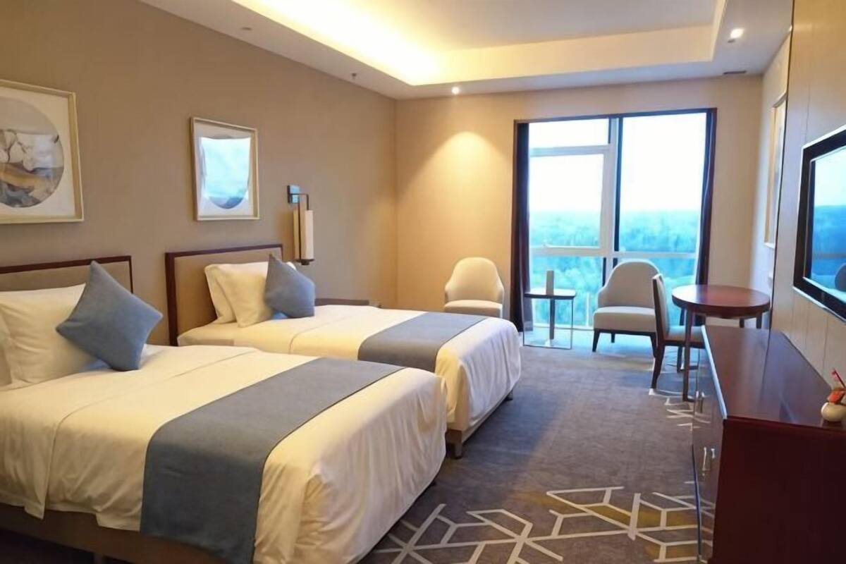 Une chambre d’hôtel avec deux lits, un bureau, une chaise et un balcon avec vue.