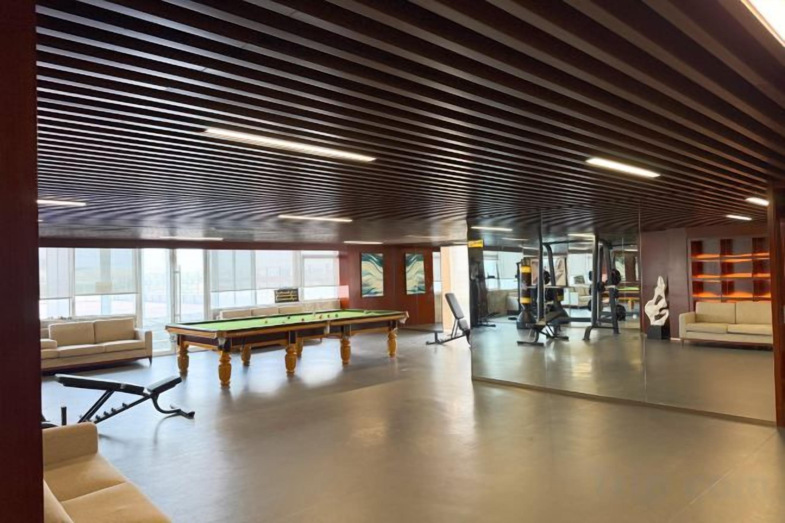 Amplio espacio interior con mesa de billar, asientos y equipo de ejercicio.